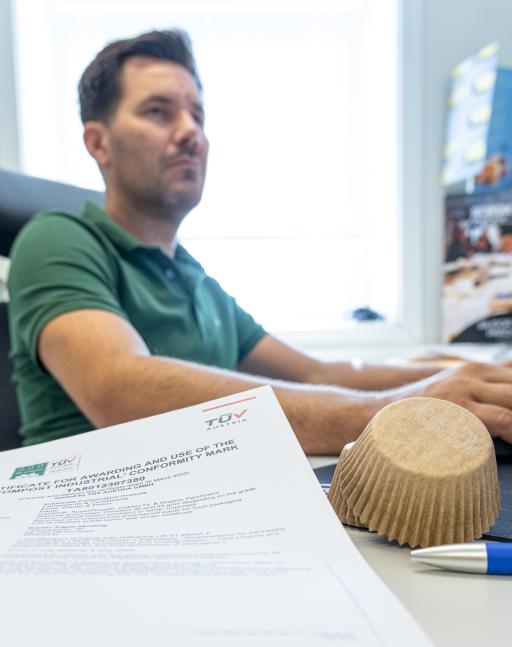 Desk with papers and a man i the background working